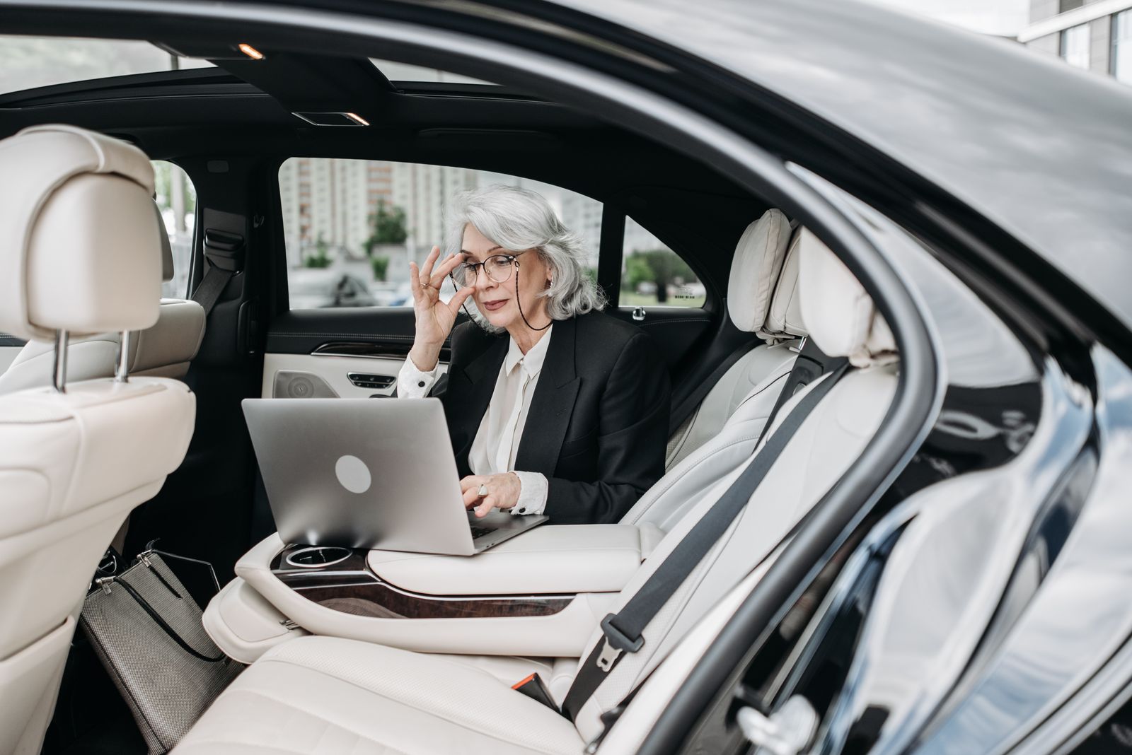 Zakenreiziger werkt op een laptop op de achterbank van een luxe taxi